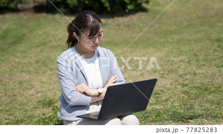 外でリモートワークをする若い女性 外でリモートワークをする若い女性 77825283