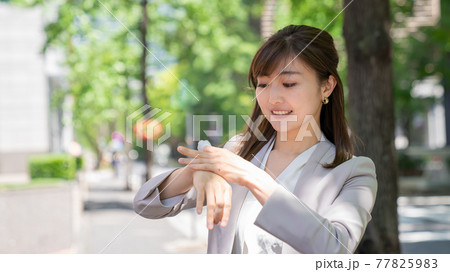 外で日焼け止めを塗る若い女性 77825983