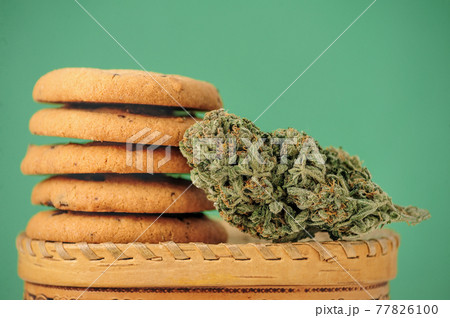 Sweets with CBD oil. Marijuana buds on green background. 77826100