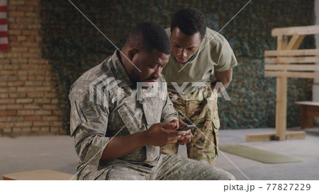 Black military men using smartphone in gym together Black military men using smartphone in gym together 77827229