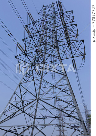High voltage tower, power line with electric cables and insulators against a blue sky  77827737