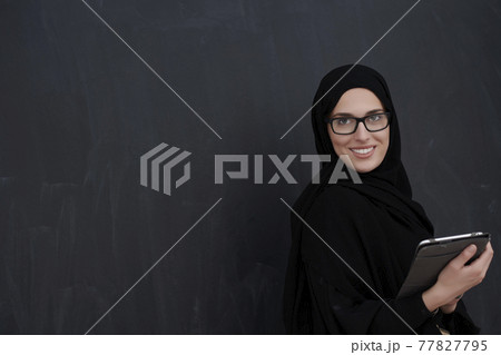 Young Arab businesswoman in traditional clothes or abaya holding tablet computer 77827795