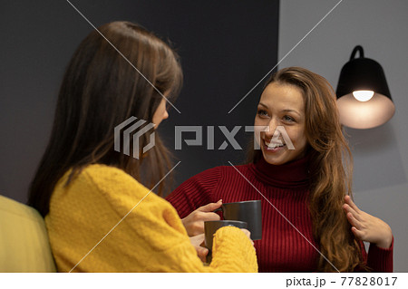 young lesbian couple talking on couch with cup of coffee 77828017