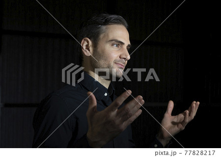 An influencer, artist and musician, dress with black shirt, poses for the camera in one of his photographic shootings for social networks, in a dark backstage area, at night, in Spain. An influencer, artist and musician, dress with black shirt, poses for the camera in one of his photographic shootings for social networks, in a dark backstage area, at night, in Spain. 77828217