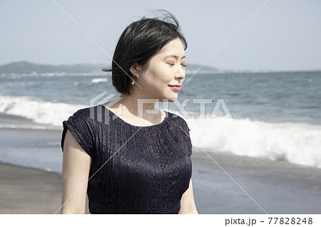 海風に吹かれながら砂浜の波打ち際を歩く若い女性(神奈川県鎌倉市七里ヶ浜) 海風に吹かれながら砂浜の波打ち際を歩く若い女性(神奈川県鎌倉市七里ヶ浜) 77828248