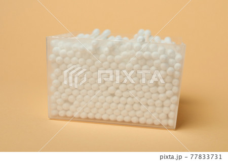 Plastic box with cotton swabs on beige background 77833731