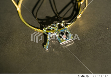 Couple set pendant necklace with a key and a lock for lovers shoot outdoors in a sunny day closeup. Selective focus Couple set pendant necklace with a key and a lock for lovers shoot outdoors in a sunny day closeup. Selective focus 77834242