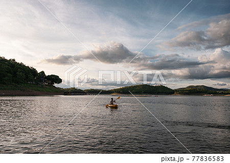 Tourist man canoeing on lake in national park at evening 77836583