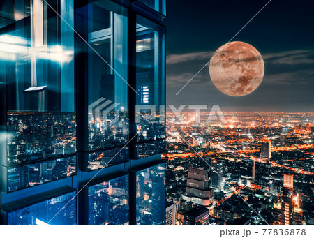 Corner glass window of skyscraper with supermoon glowing on illuminated city Corner glass window of skyscraper with supermoon glowing on illuminated city 77836878