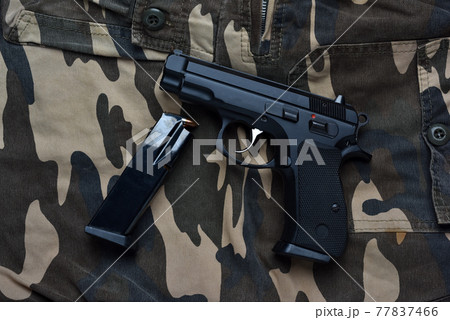 Still life with black handgun with cartridge magazine and on camouflage soldier pant background, Black semi-automatic pistol on camouflage soldier pant Still life with black handgun with cartridge magazine and on camouflage soldier pant background, Black semi-automatic pistol on camouflage soldier pant 77837466