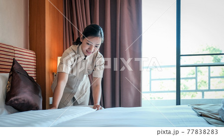 Hotel maid making the bed in the luxury hotel room ready for tourist travel Hotel maid making the bed in the luxury hotel room ready for tourist travel 77838283