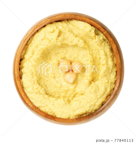 Curry hummus dip with chickpea garnish, in a wooden bowl. Middle Eastern dip, spread or savory dish made of cooked, mashed chickpeas, blended with curry powder, tahini, lemon juice and garlic. Photo. 77840113