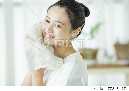 タオルで顔を拭く若い女性 77843147