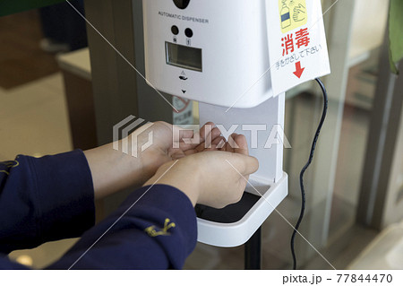 スーパー入口でアルコール噴霧器で手の消毒をする子供手元 スーパー入口でアルコール噴霧器で手の消毒をする子供手元 77844470
