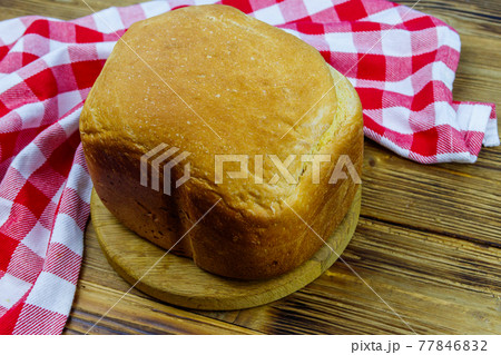 Homemade loaf of bread on a wooden table freshly baked in an electric bread maker. Homemade baking Homemade loaf of bread on a wooden table freshly baked in an electric bread maker. Homemade baking 77846832