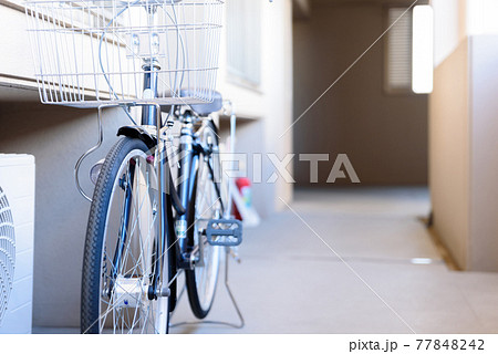 マンションの共用部分である共用廊下、 通路に自転車を置く人 マンションの共用部分である共用廊下、 通路に自転車を置く人 77848242
