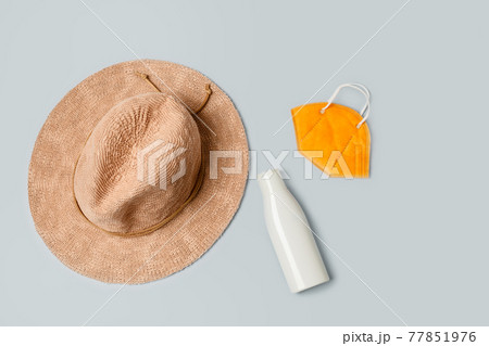 Beach accessories: straw hat, sunscreen lotion and FFP2 face mask, isolated on grey, flatlay Beach accessories: straw hat, sunscreen lotion and FFP2 face mask, isolated on grey, flatlay 77851976