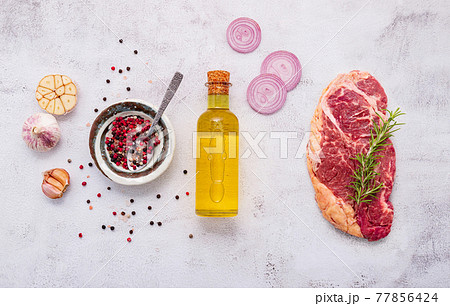 Raw Striplion Steak set up on white concrete background. Flat Lay of fresh raw beef steak with rosemary and spice on white shabby concrete background top view. Raw Striplion Steak set up on white concrete background. Flat Lay of fresh raw beef steak with rosemary and spice on white shabby concrete background top view. 77856424