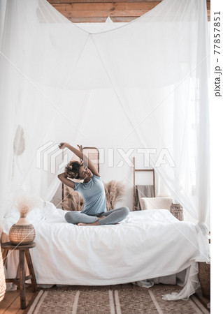 Woman sitting on bed bends to side 77857851