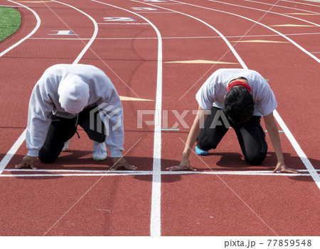 Two boys in lanes on a red track ready to run a 100 meter race at practice 77859548