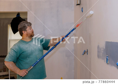 Male hand painting wall with paint roller painting apartment, renovating with color paint Male hand painting wall with paint roller painting apartment, renovating with color paint 77860444