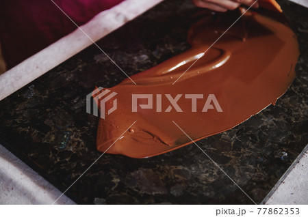 Top view of tempering chocolate mass on a dark marble surface Top view of tempering chocolate mass on a dark marble surface 77862353