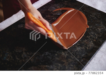 Closeup of woman's hand tempering melted chocolate on a marble surface 77862354