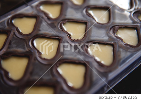 Closeup of chocolate molds in the shape of hearts full of sweet creamy filling Closeup of chocolate molds in the shape of hearts full of sweet creamy filling 77862355