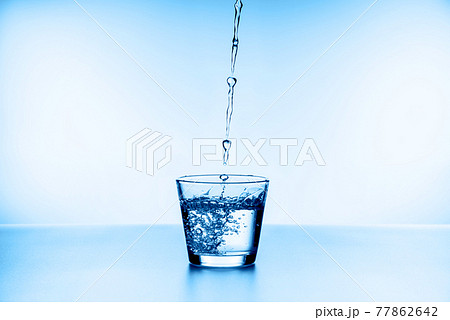 water splashing from glass isolated on blue background water splashing from glass isolated on blue background 77862642