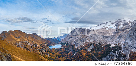 Autumn Dolomites mountain scene from hiking path betwen Pordoi Pass and Fedaia Lake, Italy. Snowy Marmolada Glacier and Fedaia Lake in far. 77864366