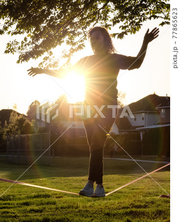 Adventurous White Caucasian Adult Woman walking on a Slackline Adventurous White Caucasian Adult Woman walking on a Slackline 77865623