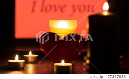 A red heart stands against a background of lighted candles and the inscription I love you. Christmas fortune telling and fortune telling. Greeting card for Valentine's day or international women's day A red heart stands against a background of lighted candles and the inscription I love you. Christmas fortune telling and fortune telling. Greeting card for Valentine's day or international women's day 77867036