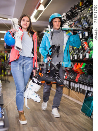 man and woman in helmets choosing sports equipment man and woman in helmets choosing sports equipment 77871730