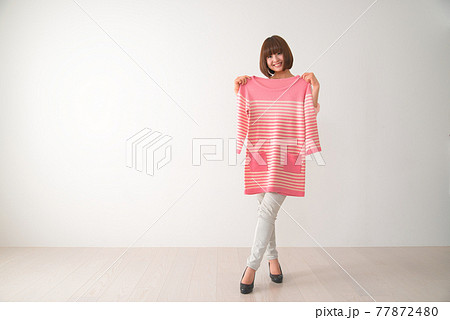 ピンク色のボーダー柄の洋服を体の前で合わせてみる若い女性 ピンク色のボーダー柄の洋服を体の前で合わせてみる若い女性 77872480