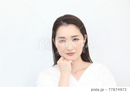 頬杖をつくカメラ目線の不安げな女性 頬杖をつくカメラ目線の不安げな女性 77874972
