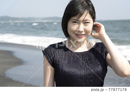 浜辺を海風に吹かれながら歩く若い女性（神奈川県鎌倉市七里ガ浜） 77877178