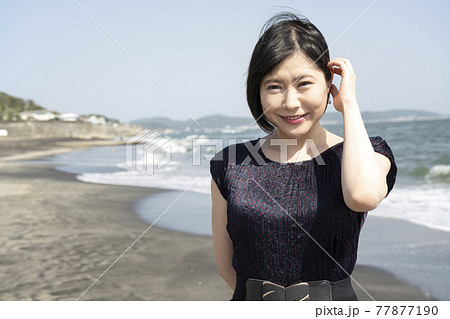 浜辺を海風に吹かれながら歩く若い女性（神奈川県鎌倉市七里ガ浜） 77877190