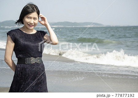 浜辺を海風に吹かれながら歩く若い女性（神奈川県鎌倉市七里ガ浜） 77877192