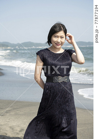 浜辺を海風に吹かれながら歩く若い女性（神奈川県鎌倉市七里ガ浜） 77877194