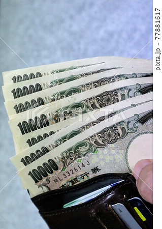財布に入った大量の一万円札のクローズアップ 77881617