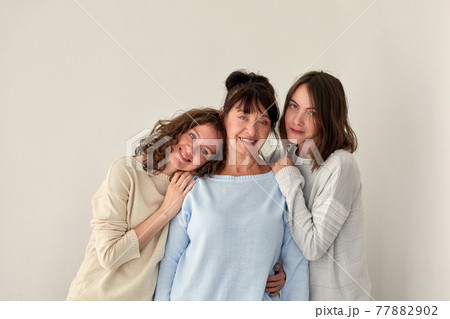 Smiling mother hugging daughters and looking at camera Smiling mother hugging daughters and looking at camera 77882902