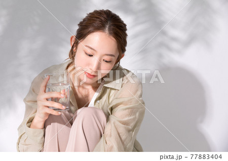 水分補給のために水の入ったグラスを手に持つ若い女性 77883404