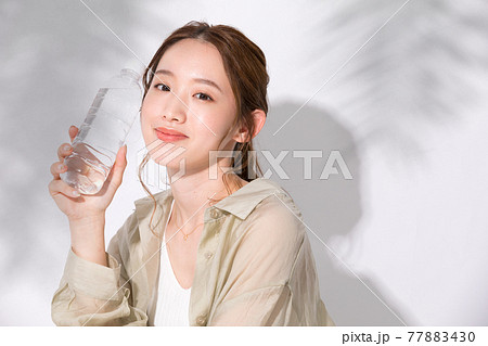 水分補給のために水のペットボトルを手に持つ若い女性 77883430