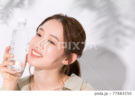 水分補給のために水のペットボトルを手に持つ若い女性 水分補給のために水のペットボトルを手に持つ若い女性 77883550