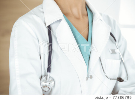 Unknown female doctor standing with arms crossed in clinic, close-up. Medicine concept 77886799