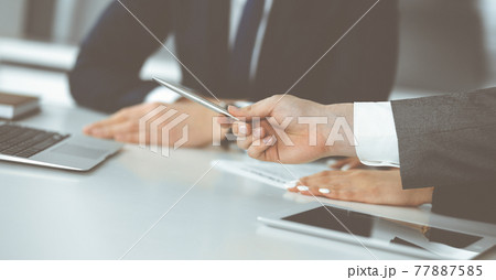 Unknown businessmen and woman sitting, using laptop computer and discussing questions at meeting in modern office, close-up 77887585