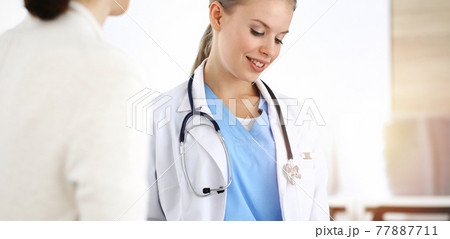Woman - doctor consults her female patient in sunny clinic 77887711