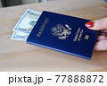 Female fingers holding American passport with dollar bills on wooden background. Travel concept. 77888872