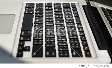 Detail of a laptop keyboard with copy space and shallow depth of field in sunlight. 77889120