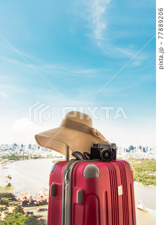 Vacation and travel. Suitcase or luggage bag with hat, Photo camera and Sun glasses with city and river view background. Vacation and travel. Suitcase or luggage bag with hat, Photo camera and Sun glasses with city and river view background. 77889206